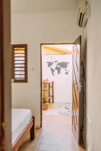 a bedroom with a door open to a room with a bed at Piano Piano hostel in Pipa