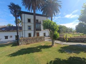 a house with palm trees and a stone wall at El Rincon de Belen in Noriega