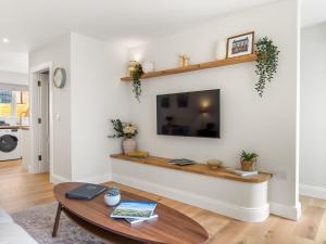 a living room with a table and a tv on a wall at The Old Forge Clifden in Clifden +35 photos
