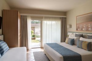 a hotel room with two beds and a large window at The Village Chia Laguna Sardinia in Chia +59 photos