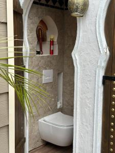 a bathroom with a toilet in a stone wall at Lodge SAHARA in Arques