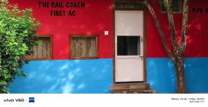 a red and blue building with a white door at The Rail Coach in Jhānsi