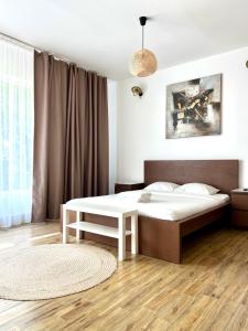a bedroom with a white bed and a table at Central Loft Studio Târgoviște in Târgovişte