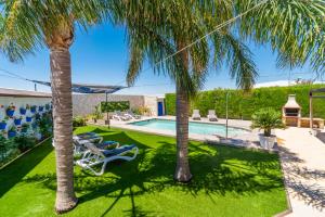 a pool with two palm trees and lounge chairs at Casa Rural Casita de la Cantera in La Lantejuela