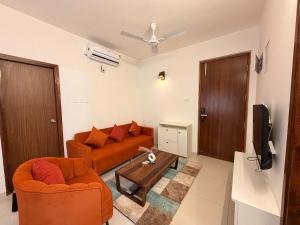 a living room with two orange couches and a tv at Casa sol Goa 2BR Apt By Amoret Homes in Chicalim