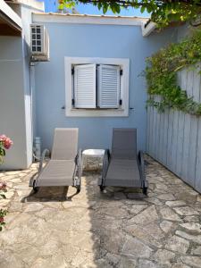 two chairs and a table in front of a blue wall at Little Blue House in Sidari