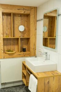 a bathroom with a white sink and wooden cabinets at Gasthaus Winzerstube & Hotel in Rödelsee +33 photos