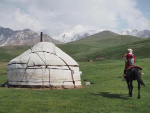 a woman riding a horse next to a yurt at Mamyr Guest House in Sary-Mogul