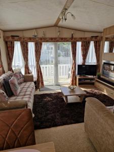 a living room with a couch and a tv at Sunblast- Dawlish Warren in Cockwood