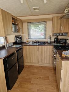 a small kitchen with wooden cabinets and a sink at Sunblast- Dawlish Warren in Cockwood