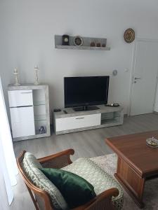 a living room with a flat screen tv and a table at Apartman Centar A in Modriča