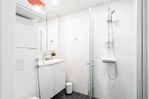 a white bathroom with a shower and a sink at Hiisi Homes Turku Fleminginkatu in Turku +39 photos