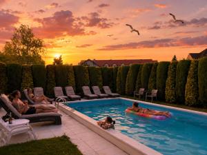 a group of people in a swimming pool at sunset at Riviera -ADULTS ONLY in Rewal +29 photos