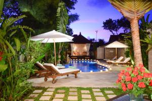 a backyard with a pool with chairs and umbrellas at Tirta Ayu Hotel and Restaurant in Tirtagangga