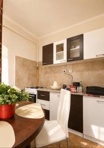 a kitchen with a wooden table and white chairs at Tófenék Deluxe Apartman in Szolnok +3 photos
