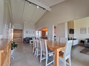 a dining room and living room with a wooden table and chairs at 4 Chaka's Rocks Chalets - The Beach Cottage in Ballito