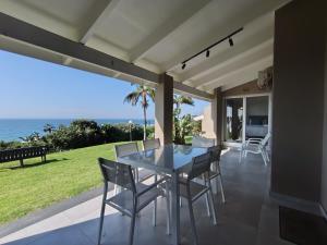 a dining room with a table and chairs on a patio at 4 Chaka's Rocks Chalets - The Beach Cottage in Ballito