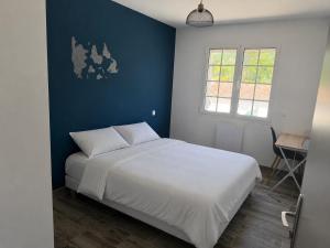 a bedroom with a white bed and a blue wall at La Couronne Apartment in La Couronne