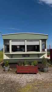 a green and white house with potted plants in it at Rowanlea Caravan in Stonehaven +7 photos