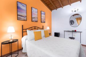 a bedroom with a white bed with orange walls at Home2Book Las Tinajas A, Peaceful Retreat in Triquivijate +13 photos