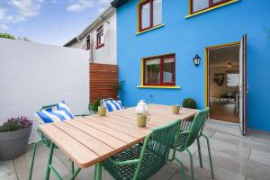 a wooden table and chairs in front of a blue house at Cottage 298 - Clifden in Clifden