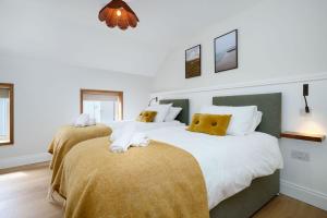 two beds in a bedroom with white and yellow pillows at Cottage 298 - Clifden in Clifden