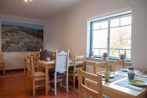 a dining room with tables and chairs and a large window at Casa Mariolas in Manteigas
