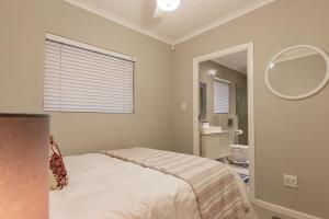 a bedroom with a bed and a bathroom with a mirror at 8 On Fleur Park Beach in Gordonʼs Bay +29 photos