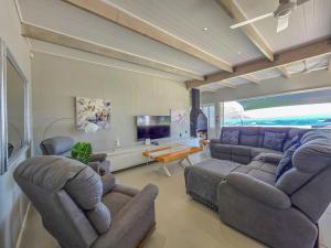 a living room with a couch and chairs and a table at 8 On Fleur Park Beach in Gordonʼs Bay