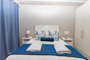 a bedroom with a large bed with blue and white pillows at 8 On Fleur Park Beach in Gordonʼs Bay