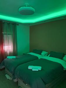 two beds in a bedroom with a green lighting at HC Home in Algeciras +27 photos