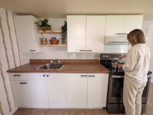 a woman standing in a kitchen looking at a stove at Chalet #2 Waterfront with Spa, Fireplace Wifi & AC in Cap-Saint-Ignace