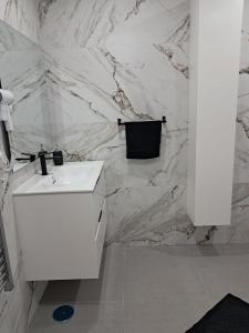 a bathroom with a white sink and a marble wall at HC Home in Algeciras
