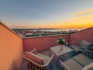 a balcony with a table and chairs and a sunset at MarAzul Apartments in Povljana