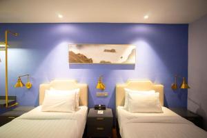 two beds in a room with a blue wall at Le Embassy Hotel Georgetown in George Town