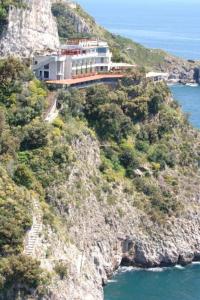 a building on the side of a mountain next to the ocean at Albergo La Conca Azzurra in Conca dei Marini