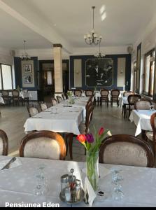 a dining room with white tables and chairs with flowers at Pensiunea Eden in Jibou