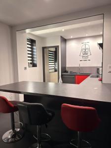 a kitchen with a large black counter with red chairs at Le 7ème Art in Hombourg-Haut