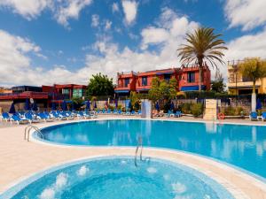 una piscina en un complejo con sillas y un edificio en Casas Meloneras by VillaGranCanaria, en Meloneras