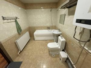 a bathroom with a toilet and a sink and a bath tub at Silk Road Hostel in Bukhara