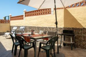 a table and chairs with an umbrella on a patio at Casa Be in Caleta De Fuste