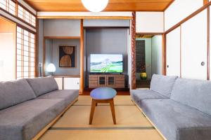 a living room with a couch and a tv at 湯のん - Yunon - 温泉付き一棟貸し古民家 指宿名物 砂むし温泉徒歩2分 最大11名 in Ibusuki