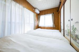 two beds in a room with a window at 湯のん - Yunon - 温泉付き一棟貸し古民家 指宿名物 砂むし温泉徒歩2分 最大11名 in Ibusuki