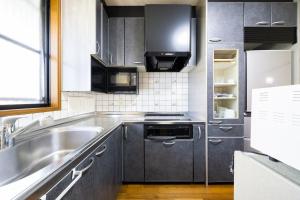a kitchen with stainless steel appliances and a sink at 湯のん - Yunon - 温泉付き一棟貸し古民家 指宿名物 砂むし温泉徒歩2分 最大11名 in Ibusuki