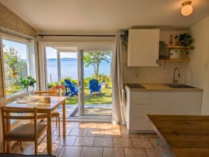 a kitchen and dining room with a table and a view of the ocean at Chalet Studio #3 Waterfront with Spa, Fireplace & Wifi in Cap-Saint-Ignace