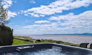a bath tub sitting next to a body of water at Chalet Studio #3 Waterfront with Spa, Fireplace & Wifi in Cap-Saint-Ignace +30 photos