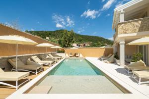 a swimming pool with chairs and umbrellas next to a building at Borgo Myricae in Chia
