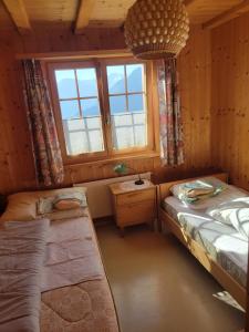 a small room with two beds and a window at Chalet Heinzenberg in Urmein