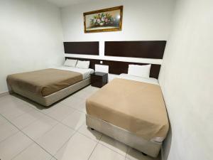 a room with two beds in a room at Tropicana Inn in Sitiawan