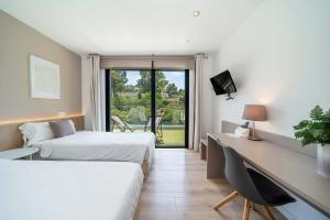 a hotel room with two beds and a desk and a window at Villa SP1 Suites Santa Ponsa by Sealand Villas in Santa Ponsa +42 photos